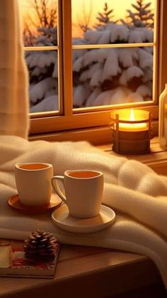 two cups and saucers sitting on a table next to a window with snow outside