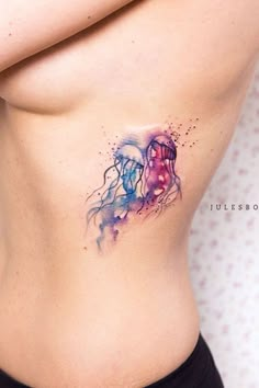 a woman's stomach with watercolor tattoos on it