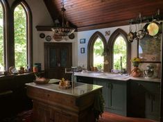 a kitchen with an island in front of two large arched windows and wooden flooring