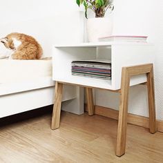 an orange and white cat sitting on top of a bed next to a shelf with records