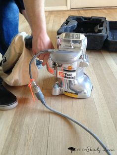 a person is working on a wood floor with a sander and other items in the background