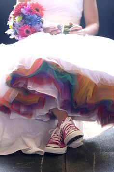 the bride is sitting down with her colorful wedding dress on and shoes in front of her