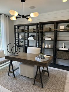 a room with shelves, chairs and a desk in the middle of it is lit by three lights