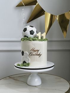 a soccer themed birthday cake on a table with gold streamers and confetti