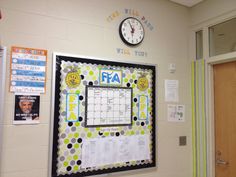 a bulletin board is hanging on the wall next to a clock and other school supplies