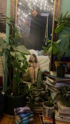 a woman sitting on a bed in front of a mirror with potted plants next to her