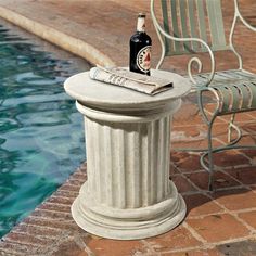 a bottle of beer sitting on top of a white pedestal next to a swimming pool