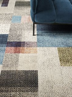 a blue couch sitting on top of a carpet covered in lots of different colored squares