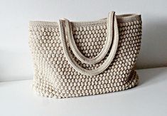 a crocheted purse sitting on top of a white table next to a wall