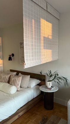 a bed with white sheets and pillows next to a small side table in a room