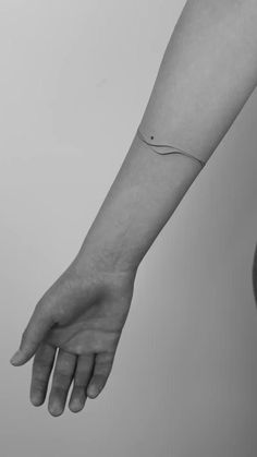 a person's arm with a small wave tattoo on the left wrist and an apple in the background