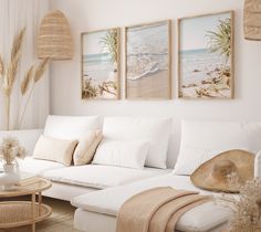 a living room filled with white furniture and paintings on the wall above it's couch