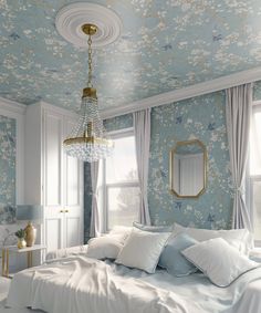 a bedroom with blue and white wallpaper, gold chandelier and bedding