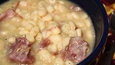 a bowl filled with beans and ham on top of a table