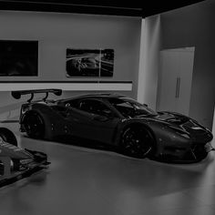 a black and white photo of a sports car in a garage with two other cars