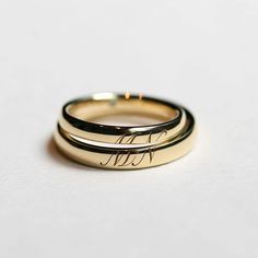 two gold wedding bands with the word love engraved on them, sitting next to each other