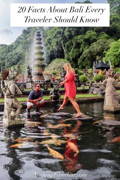 a man and woman walking through a pond with goldfish in it