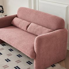 a pink couch sitting on top of a rug