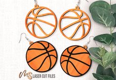 three hoop earrings with basketballs on them are hanging from hooks next to a plant