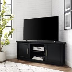 a flat screen tv sitting on top of a black entertainment center next to a potted plant