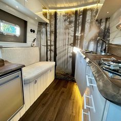 the interior of a camper trailer with wood flooring and white cabinets is shown