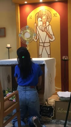 a woman kneeling on the floor in front of a church altar with an image of jesus behind her