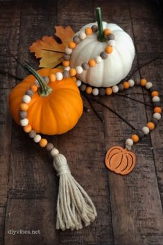 some pumpkins and other decorations on a wooden floor with beads, tassels and leaves