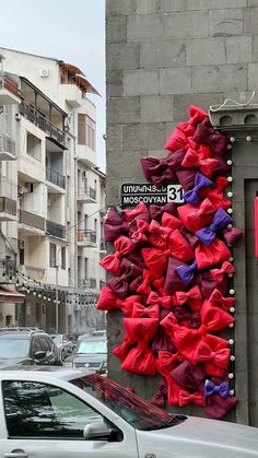 a bunch of red and purple bow ties hanging on the side of a building