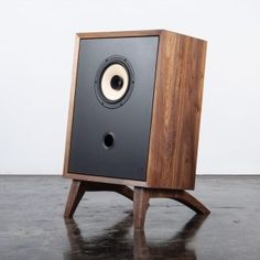 a wooden speaker sitting on top of a black table next to a white wall and floor