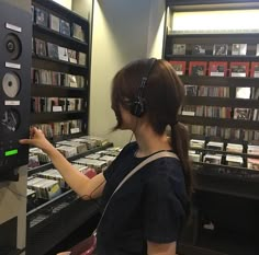 a woman wearing headphones is looking at cd's in a record store aisle