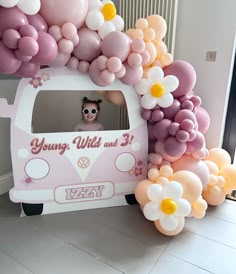 a vw bus decorated with balloons in the shape of flowers and daisies for a birthday party