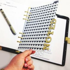 someone is holding a notebook with the word project written in gold foil on it, next to a pen and notepad