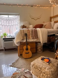 a bedroom with a bed, desk and guitar on the floor in front of it