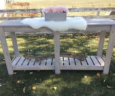 a wooden table with a planter on top and some flowers in the vase next to it