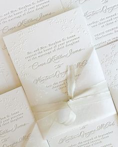 the wedding stationery is laid out on top of each other, and tied together with a white ribbon