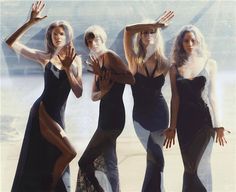 four women dressed in black and white posing for the camera with their hands raised up