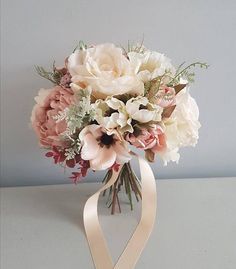 a bouquet of flowers in a glass vase with a ribbon tied around the bottom half