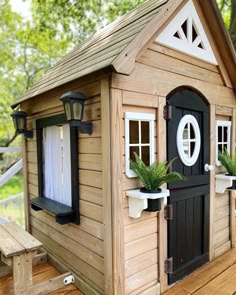 a small wooden house sitting on top of a wooden floor next to a bench and trees