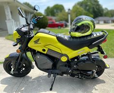 a yellow and black motorcycle parked in front of a house with a helmet on it's seat