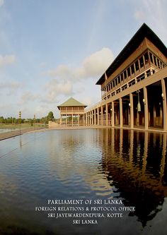 a large building sitting next to a body of water with columns on each side and the words parliament of sri lanka written below it