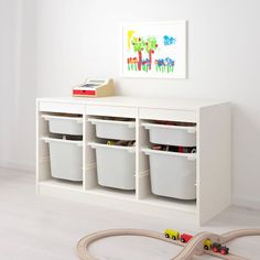 a toy train set sitting on top of a white shelf next to green bins