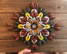 a person is holding up a multicolored flower made out of crayons