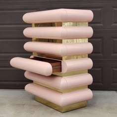 a tall pink and gold sculpture sitting in front of a garage door on top of cement