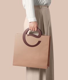 a woman holding a brown bag with the letter c on it