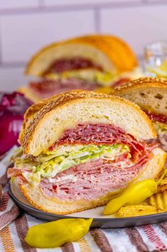 a sandwich with meat, cheese and lettuce on a plate next to chips