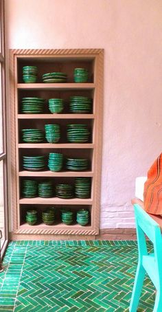 a room with green plates on shelves and a blue chair