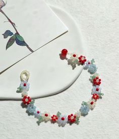 the beaded bracelet is laying on top of a white plate with red, blue and green beads