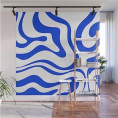 an abstract blue and white wall mural in a living room with wooden floors, a ladder and potted plant