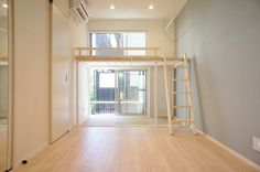 an empty room with wooden floors and ladders to the second floor, in front of a sliding glass door