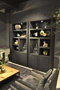 a living room filled with lots of furniture next to a wall mounted bookcase full of vases